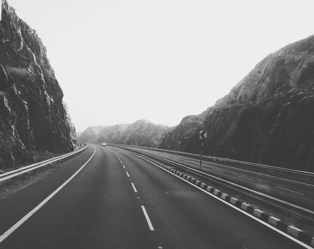 Black-and-white photo of an empty road leading between steep rock walls into the mountains