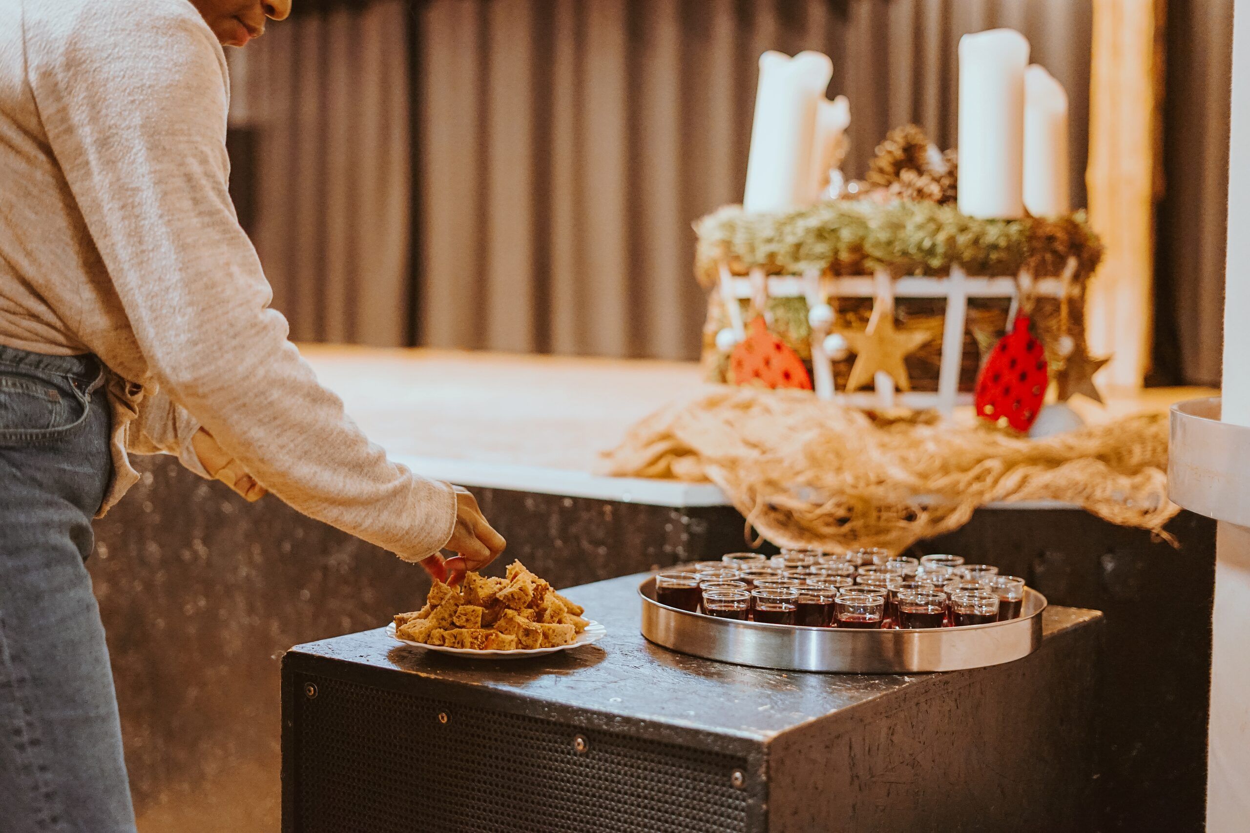 Someone taking bread for communion next to a tray of small cups