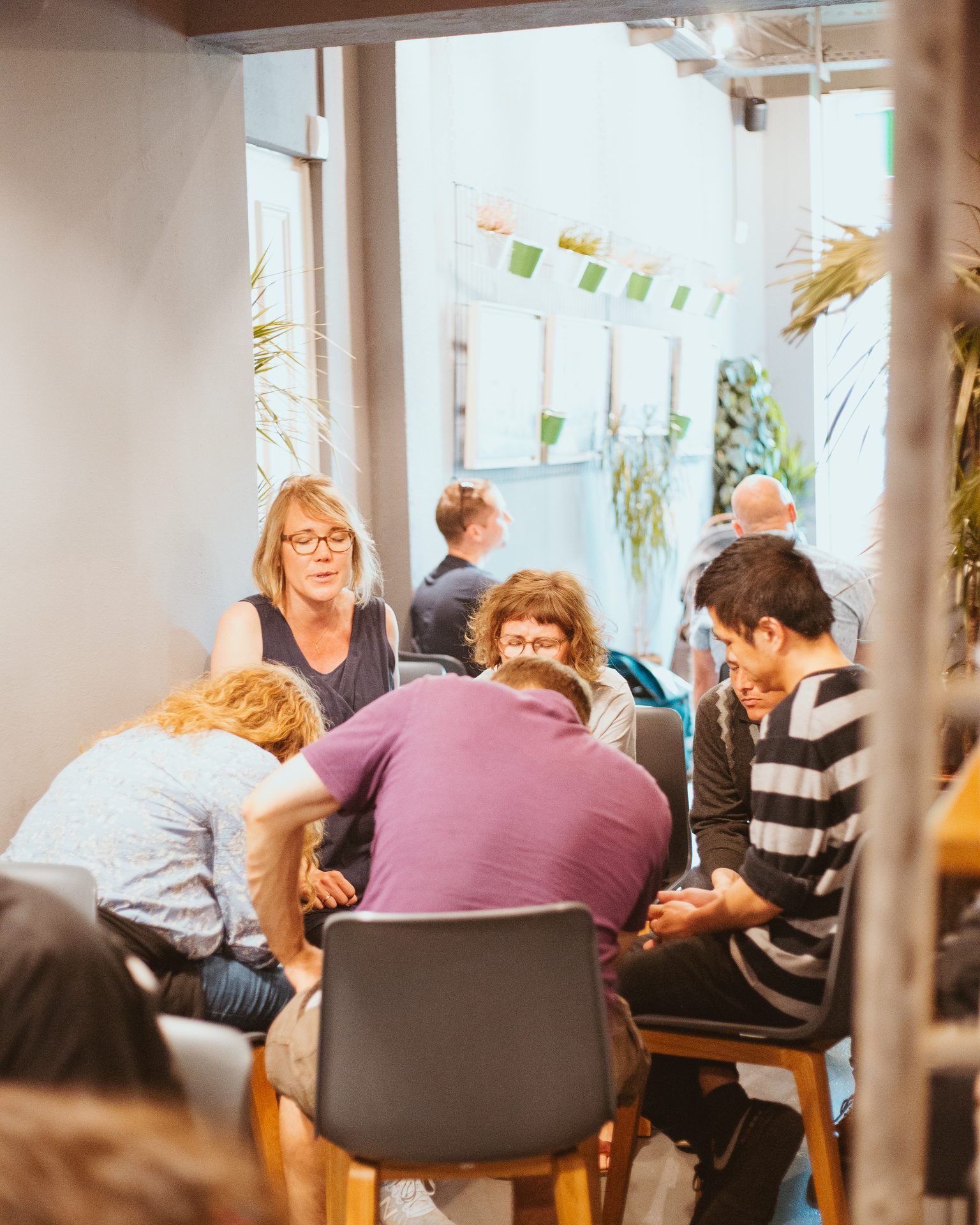 A small group sitting on chairs in a circle, praying