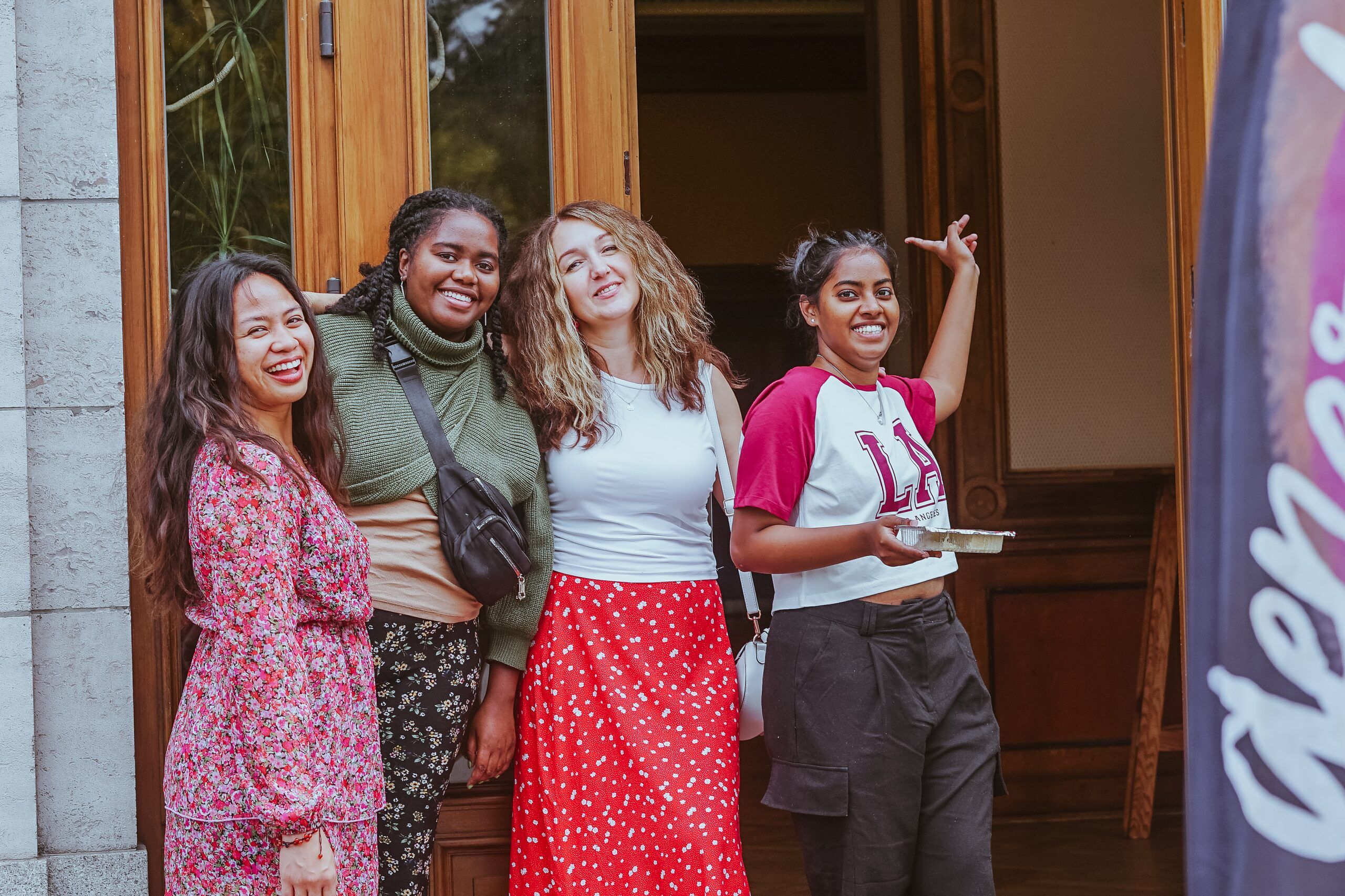Four young women laughing together in the doorway