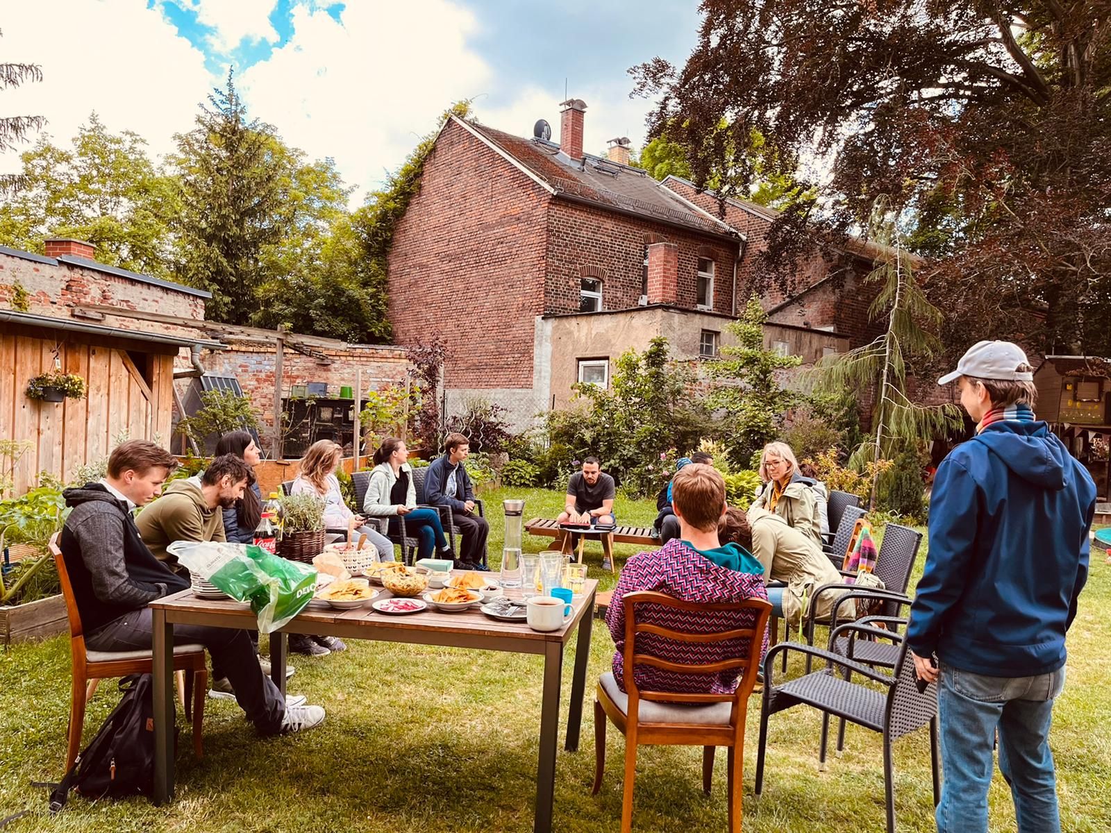People from many nations sitting together at tables in a sunny garden
